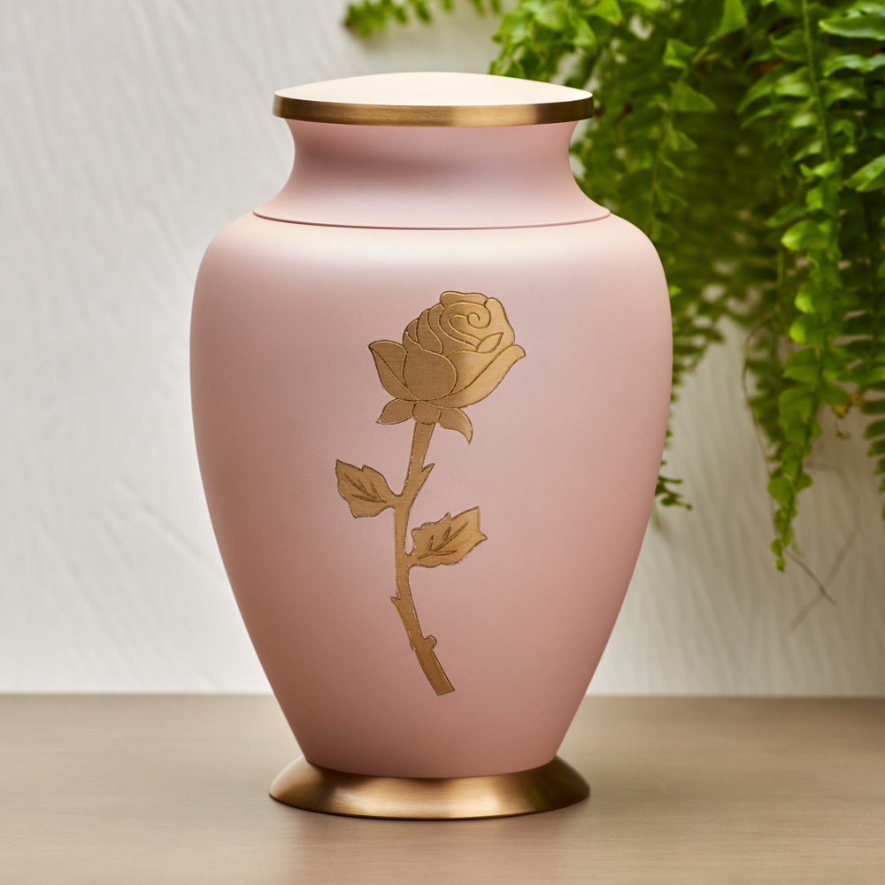 Brass cremation urn featuring a shimmering pink finish, gold accents, and a golden rose lifestyle.