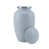 Classically shaped whitish grey urn with the threaded lid leaning against the side showing where ashes are inserted.