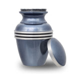 Threaded lid of light blue small keepsake urn leaning up against side of the urn, revealing the compartment for storing ashes.