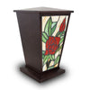 Stained glass cremation urn featuring intricate rose design laid on a brown polyresin urn body.